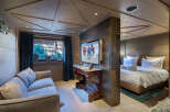 Experience luxury mountain living in this beautifully appointed suite, featuring a plush sofa and a large flat-screen TV displaying vibrant ski imagery.