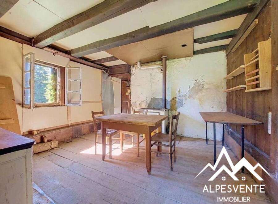 Discover this charming rustic interior featuring exposed wooden beams and a traditional wood-burning stove, perfect for a cozy mountain retreat.