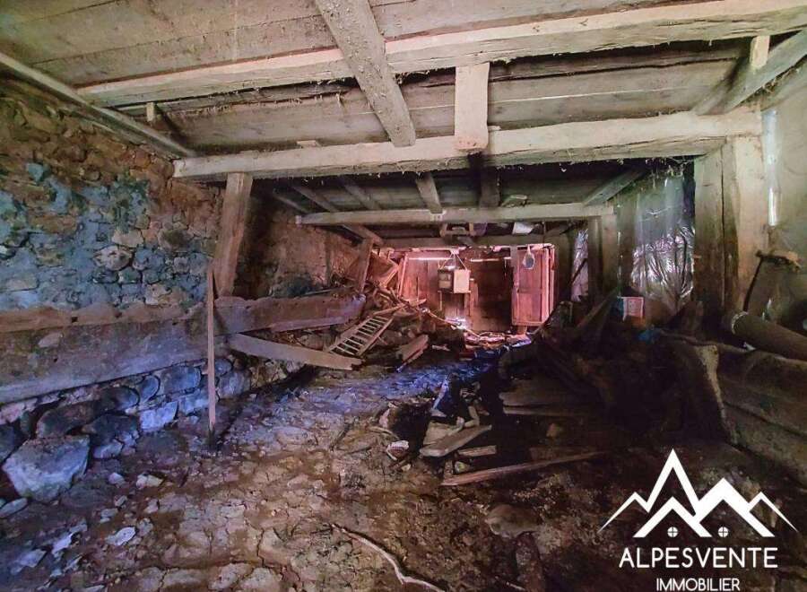 Explore the potential of this rustic property, featuring exposed stone walls and sturdy wooden beams, offering a unique renovation opportunity.
