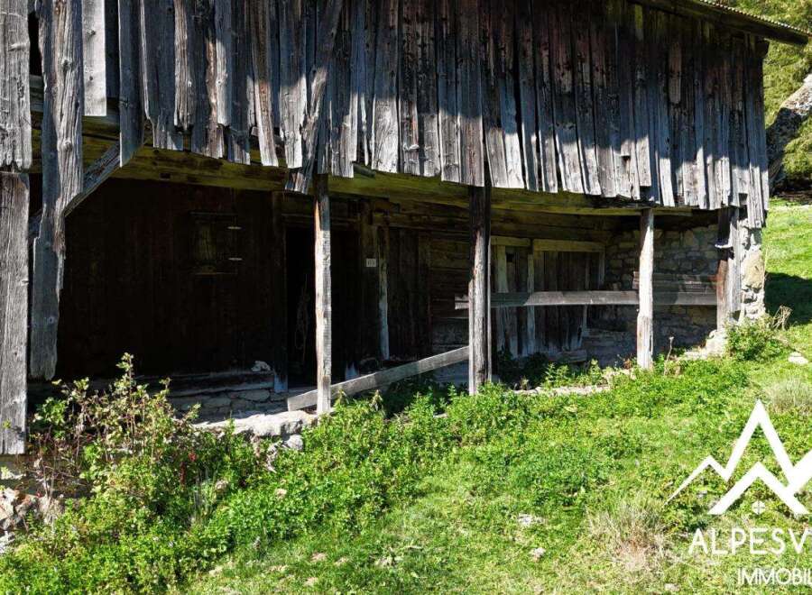 Discover this rustic wooden barn, nestled in a lush green landscape.
