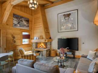 Experience cozy mountain living in this charming chalet living room, featuring a magnificent stone fireplace and exposed wooden beams.