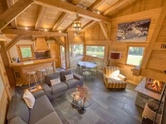 Experience rustic charm in this stunning wooden chalet, featuring a cozy living area with a fireplace and a modern kitchen island.