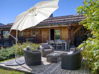 Enjoy outdoor living on this charming wooden deck, complete with comfortable wicker seating and a large patio umbrella for shade.