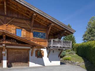 Experience rustic charm in this stunning wooden chalet, featuring a spacious garage and a picturesque balcony overlooking lush greenery.