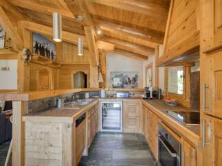 Experience rustic charm in this beautifully appointed wooden kitchen, featuring a spacious island, modern appliances including a wine cooler and coffee machine, and a sleek induction stovetop.