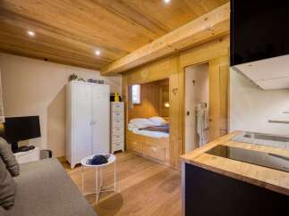 Discover this charming studio apartment featuring a cozy built-in bed nook with wooden accents and decorative carvings.