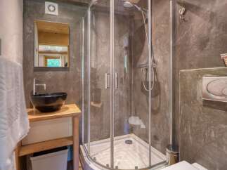 Experience modern comfort in this stylish bathroom, featuring a sleek glass shower enclosure and a contemporary black vessel sink atop a wooden vanity.