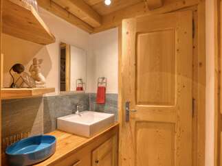 Discover this charming bathroom featuring a modern square vessel sink atop a warm wooden vanity.