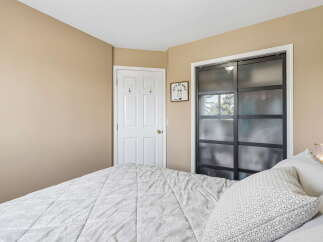 This bedroom features a cozy bed with a patterned comforter and decorative pillows, perfect for relaxation.