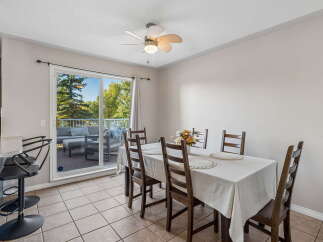 Enjoy seamless indoor-outdoor living with this inviting dining area, featuring a sliding glass door that opens to a spacious deck overlooking lush greenery.