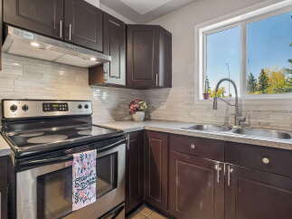 This kitchen features dark wood cabinets and a sleek stainless steel range with a modern backsplash.