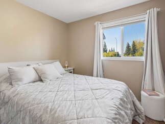 This cozy bedroom features a comfortable queen-size bed with plush white bedding and decorative pillows, perfect for a restful night's sleep.