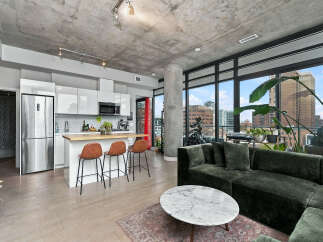 Experience modern urban living in this stylish open-concept condo featuring a sleek, high-gloss kitchen with stainless steel appliances and a breakfast bar.