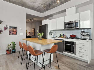 Experience modern urban living in this sleek condo kitchen, featuring high-gloss white cabinetry and stainless steel appliances.