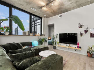 Experience modern urban living in this stylish loft featuring a spacious sectional sofa and a large window with city views.