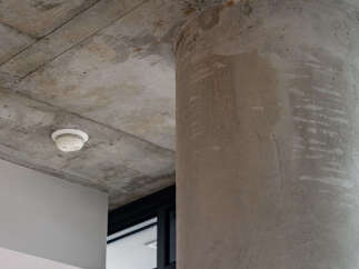 Experience modern living with this stunning property featuring exposed concrete elements, including a robust cylindrical pillar and a textured ceiling.