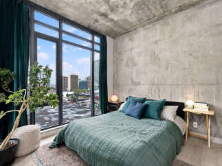 Experience urban living in this stylish bedroom featuring a plush green quilt and a collection of accent pillows.