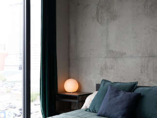 Experience modern urban living in this stylish bedroom featuring a plush, quilted bed with deep teal and navy accent pillows.