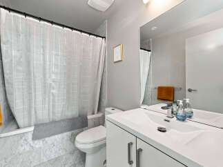This modern bathroom features a sleek white vanity with ample storage and a double sink, complemented by a large mirror reflecting the clean lines of the space.