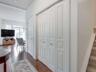 Step into a bright and airy living space featuring a large flat-screen TV mounted above a wooden storage bench.