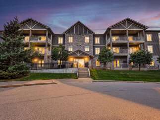 Experience modern living in this stunning condo building, featuring elegant stone and siding exteriors under a twilight sky.