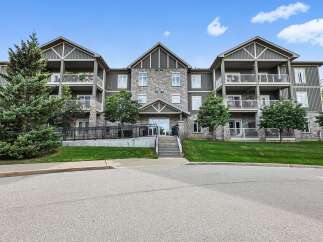 Discover modern living in this stunning apartment building, featuring a stone and dark siding exterior with multiple balconies offering scenic views.