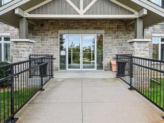 This property features a welcoming entrance with double glass doors, complemented by a stone facade and a covered porch.