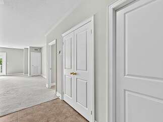 Step into this inviting hallway featuring a double door closet with elegant gold knobs, perfect for ample storage.