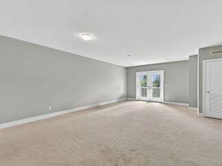 This spacious room features neutral-toned carpeting and light gray walls, creating a serene and versatile atmosphere.
