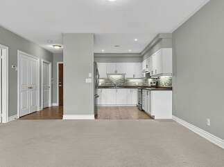 Step into this beautifully appointed home featuring a modern white kitchen with sleek cabinetry and a stylish backsplash.