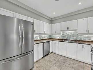 This modern kitchen boasts sleek white cabinetry and a stunning glass tile backsplash that adds a touch of elegance.