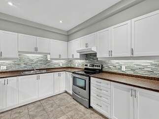 This modern kitchen boasts sleek white cabinetry and a stunning mosaic tile backsplash that adds a touch of elegance.