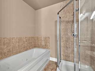 Experience luxury and relaxation in this bathroom featuring a spacious jacuzzi tub and a separate glass-enclosed shower.