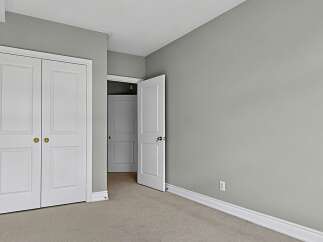 This image showcases a bedroom with a neutral color palette, featuring light gray walls and beige carpeting.