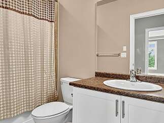 This bathroom features a modern vanity with a granite countertop and a sleek white sink, complemented by a white toilet and a stylish polka dot shower curtain.