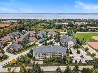 Discover this stunning aerial view showcasing a modern condominium complex nestled amidst lush greenery and mature trees.