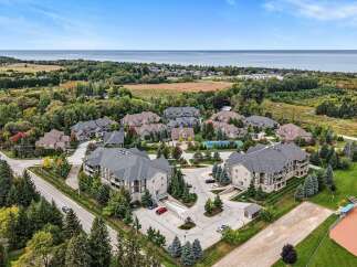Discover this stunning aerial view of a modern condominium complex nestled amidst lush greenery and mature trees.
