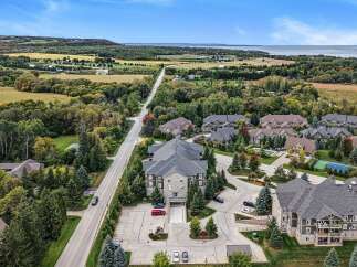 Experience luxury living in this stunning aerial view of a modern condominium complex nestled amidst rolling hills and lush greenery.
