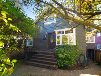 Charming home with a welcoming entrance featuring dark wood steps leading to a dark wood door with a diamond-shaped window.