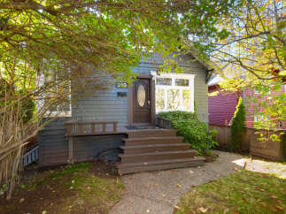 Charming home with a welcoming dark brown front door and a large bay window.