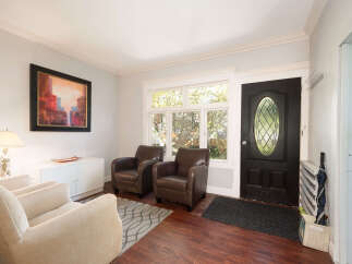 Step into a welcoming entryway featuring a stylish black front door with an oval glass insert, complemented by a large window that floods the space with natural light.