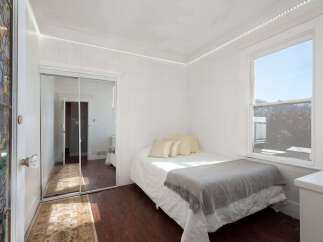 Step into this charming bedroom featuring a comfortable bed adorned with plush pillows and a cozy gray throw blanket.