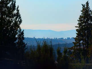 Discover breathtaking panoramic views of a distant city skyline nestled amongst rolling hills and lush forests.