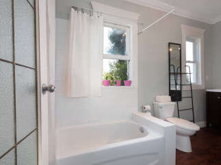 This bright and airy bathroom features a spacious bathtub with white tiled walls, perfect for a relaxing soak.