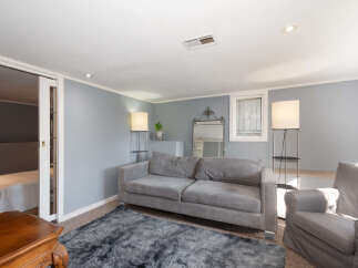 This inviting living space features a plush gray sofa adorned with nailhead trim, complemented by a soft, dark gray shag rug.