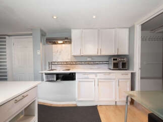 Discover this charming kitchen featuring white cabinetry and a sleek tiled backsplash.