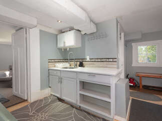 Discover a functional and charming space featuring a convenient sink and ample cabinet storage, perfect for laundry or utility needs.