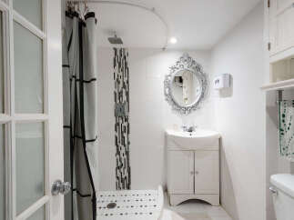Discover this charming bathroom featuring a spacious walk-in shower with a decorative tile accent and a sleek shower head.