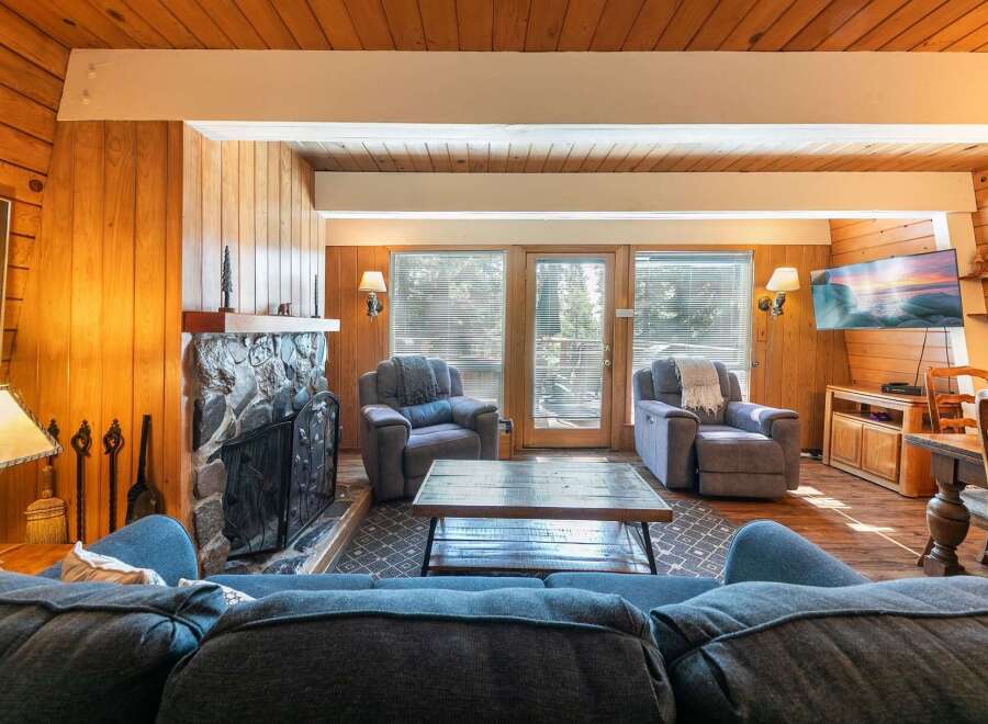 Cozy living room featuring a stone fireplace and warm wood paneling.