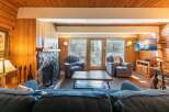 Cozy living room featuring a stone fireplace and warm wood paneling.